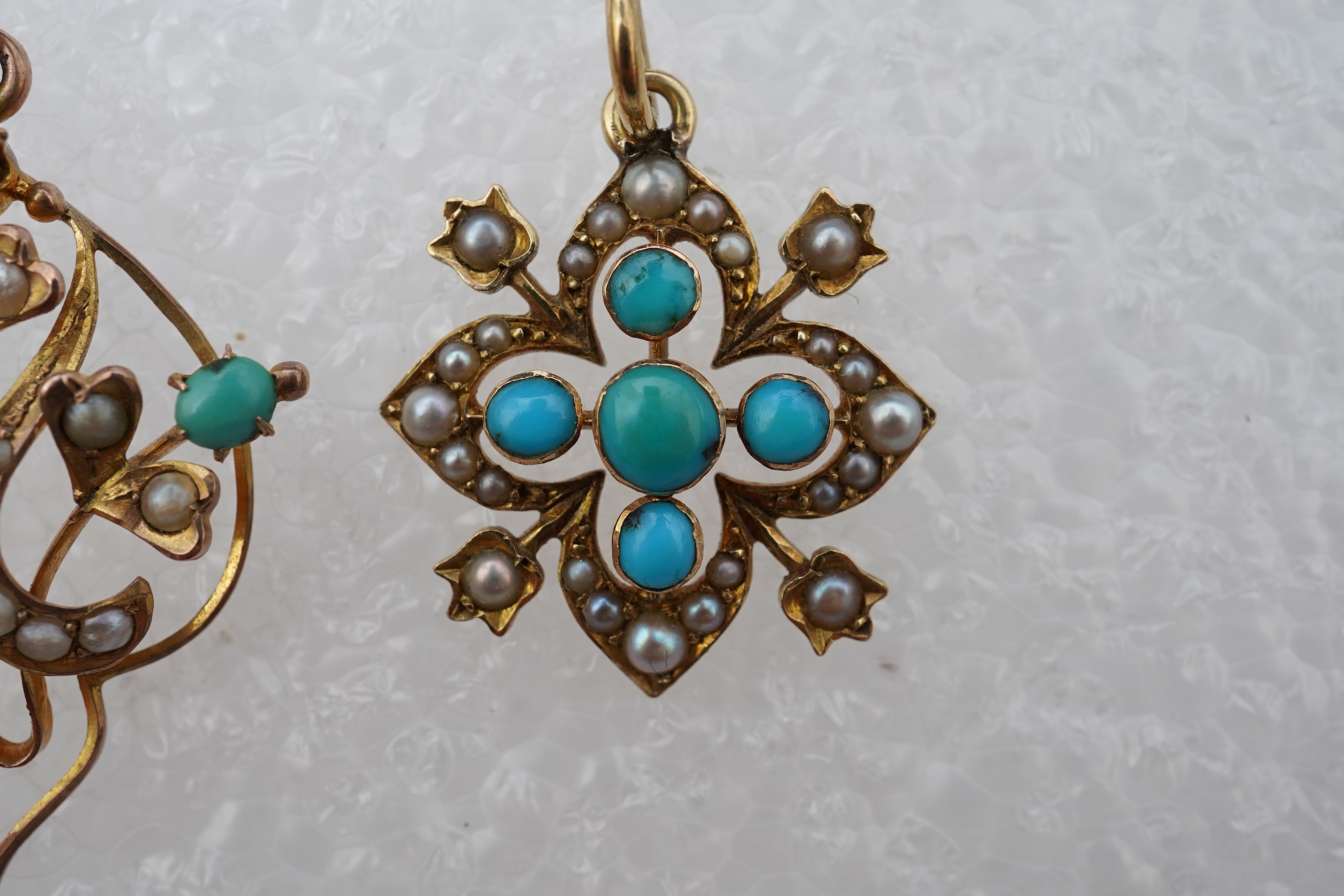 Two Edwardian turquoise and seed pearl pendants, each of foliate design, set with turquoise cabochons and seed pearls, mounted in gold, longest 3.7cm, smaller stamped 15CT, combined gross weight approximately 4 grams